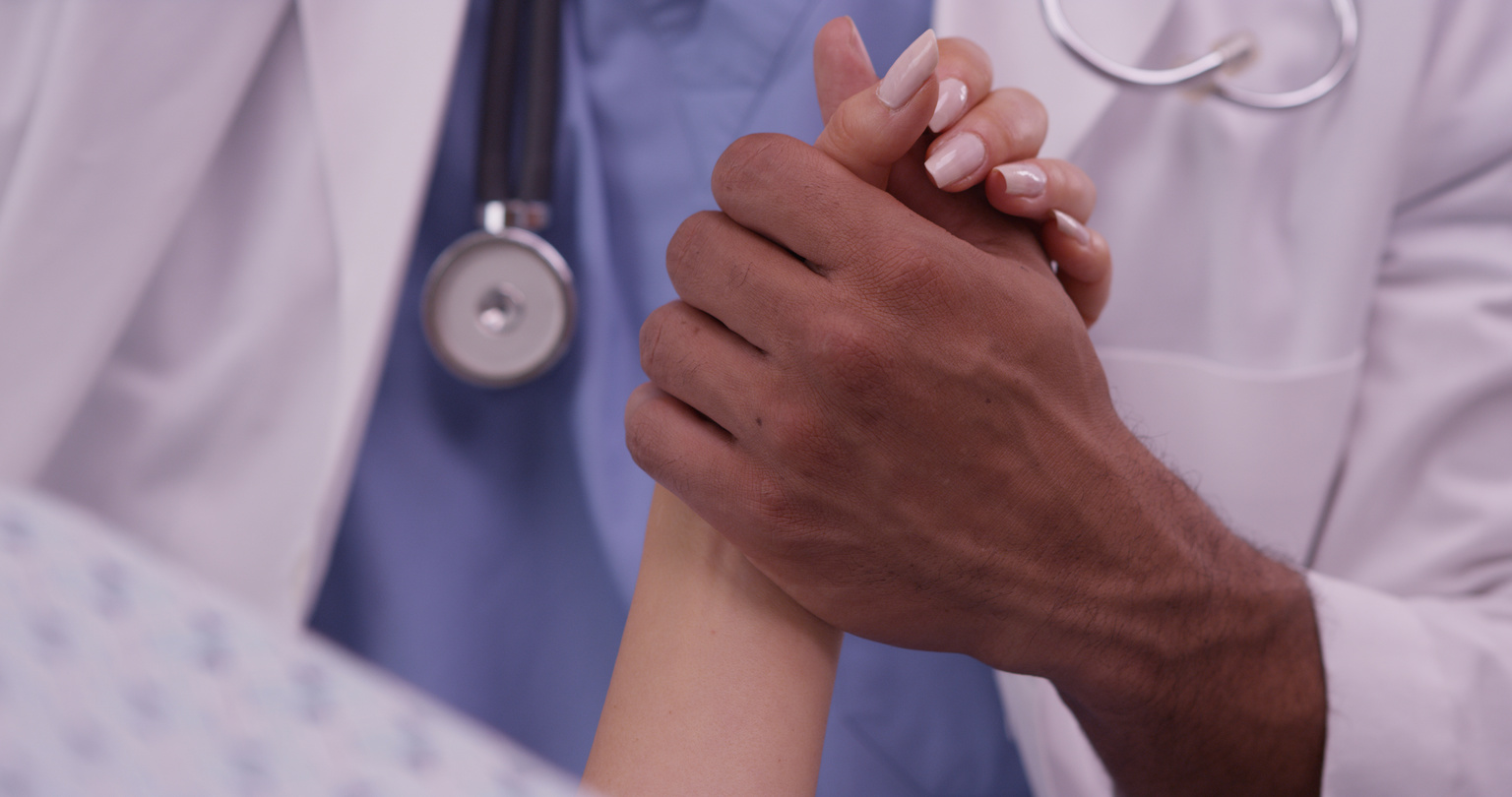 Black doctor holding patient's hand