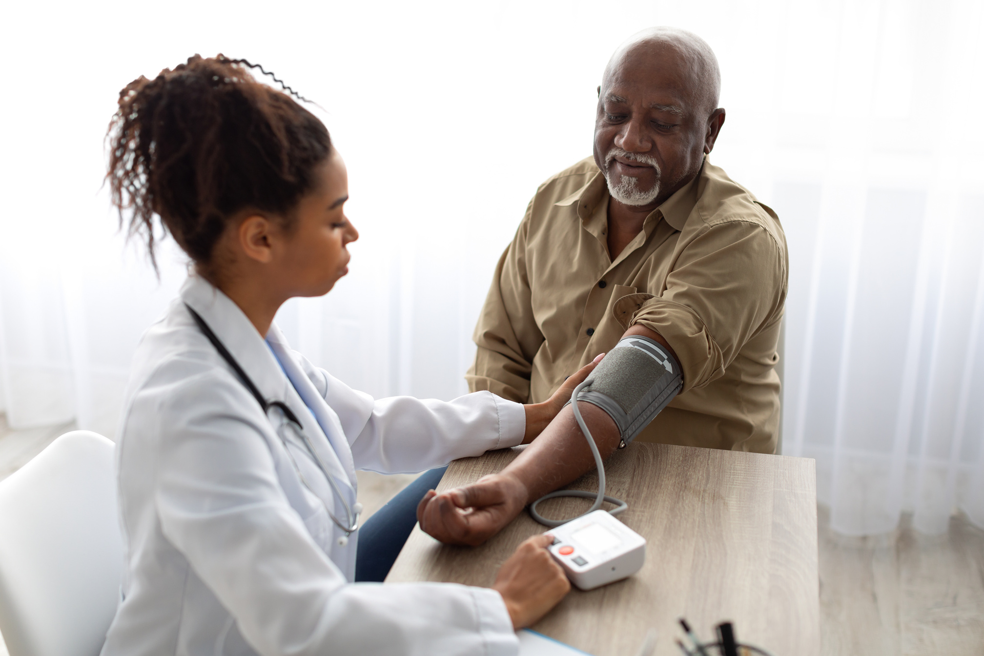 Black female doctor checking measuring pressure on patient's hand